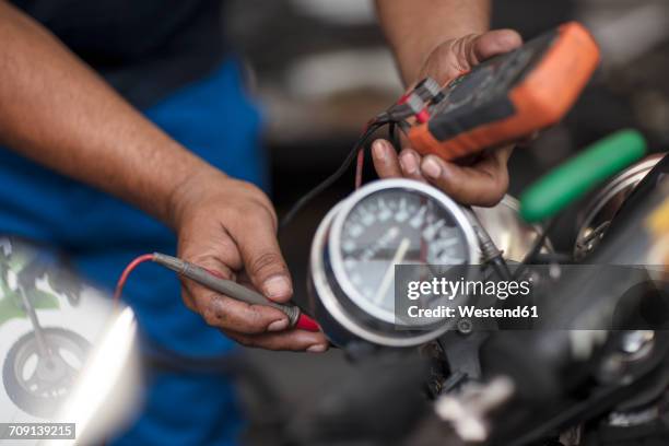 mechanic in motorcycle workshop holding a voltage meter - voltmeter stock pictures, royalty-free photos & images
