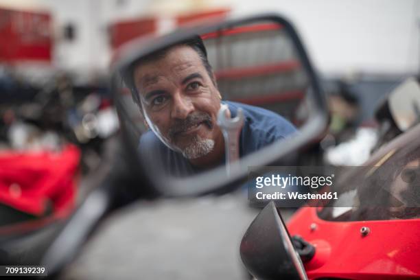 confident mechanic in workshop reflected in wing mirror - motorcycle mechanic stock pictures, royalty-free photos & images