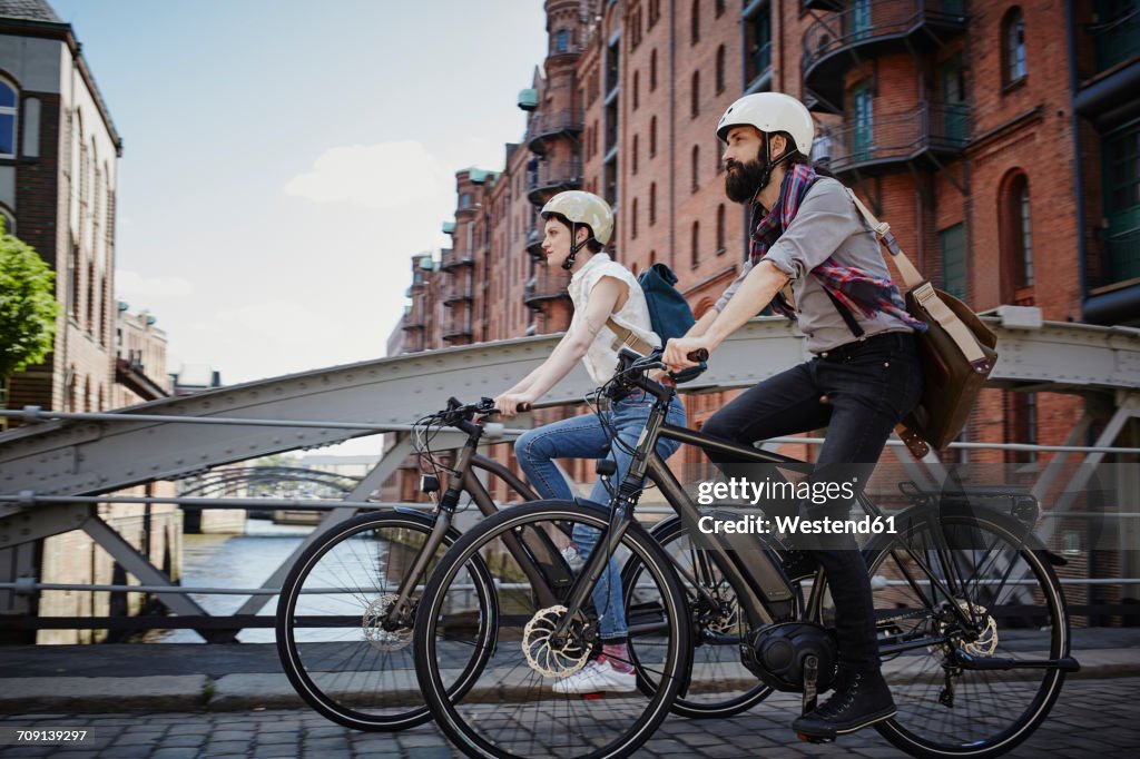 Germany, Hamburg, couple riding electric bicycles at Old Warehouse District