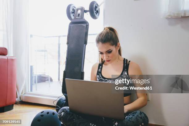 young woman using laptop while electric skateboard is chragig - electric skateboard stock pictures, royalty-free photos & images
