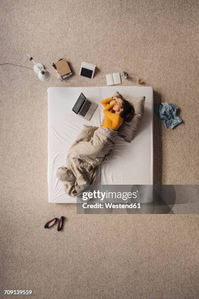 woman lying in bed next to laptop, top view - matras stockfoto's en -beelden