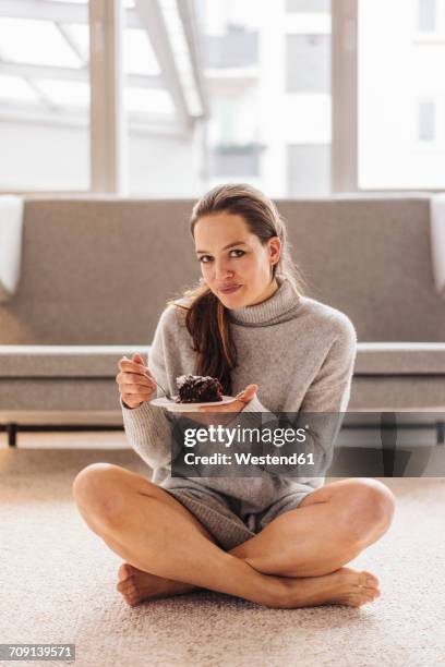 portrait of woman sitting on floor eating piece of cake - parte del cuerpo humano fotografías e imágenes de stock