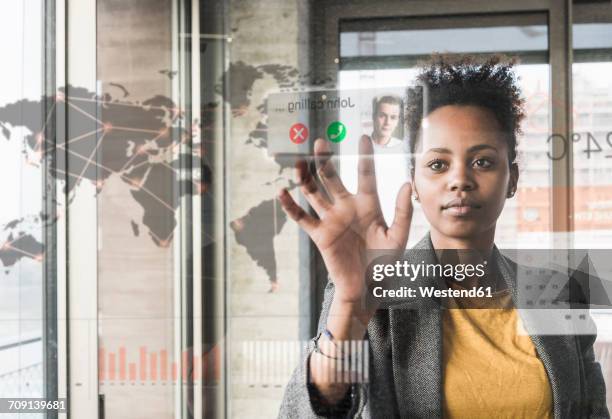 young woman receiving a call on glass wall with world map in office - touch map stock-fotos und bilder