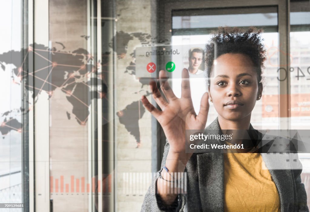 Young woman receiving a call on glass wall with world map in office