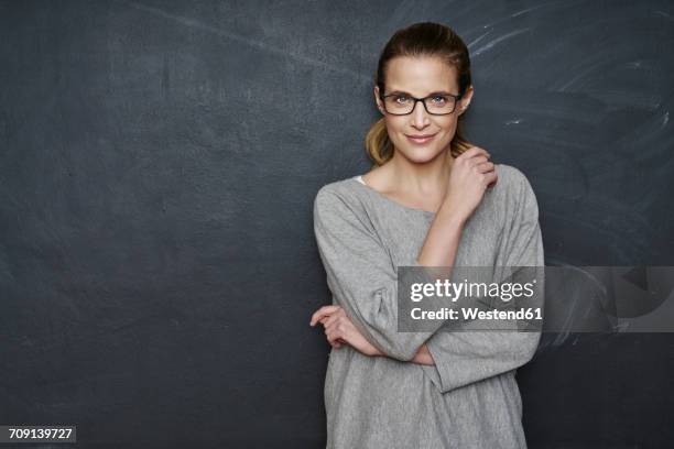 portrait of smiling woman standing in front of blackboard - teacher studio portrait stock-fotos und bilder