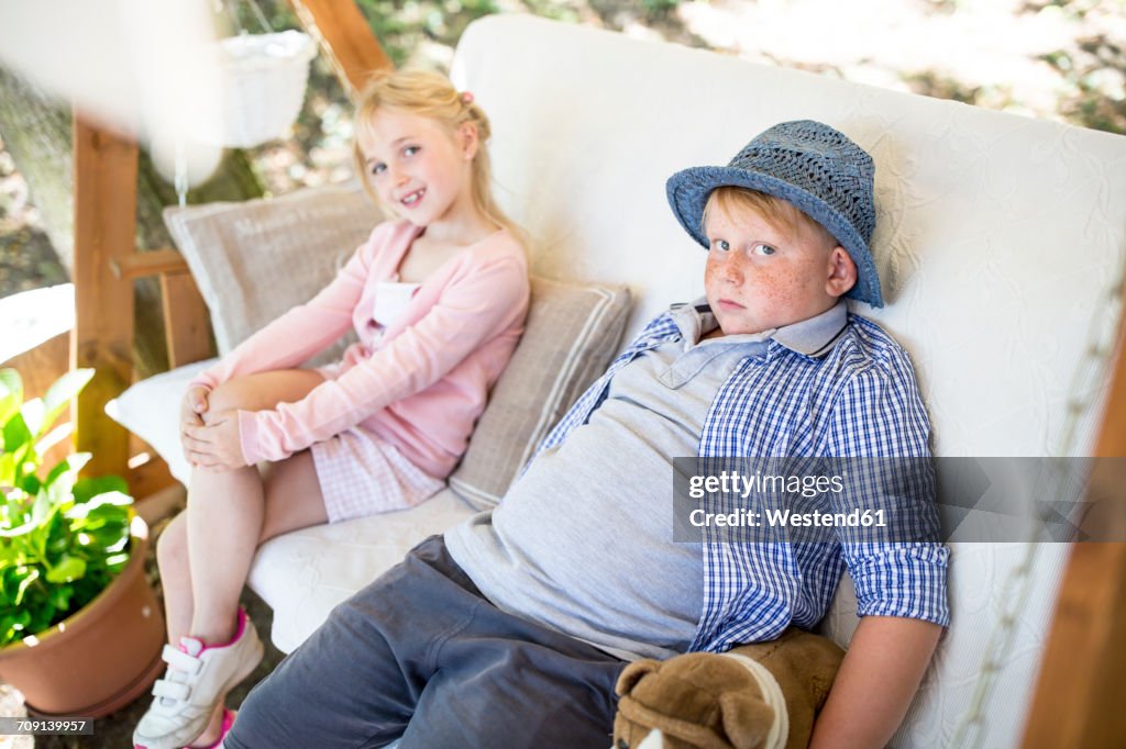 Sister and brother sitting in canopy swing