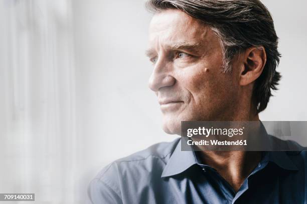 mature businessman looking away - contemplation window stock-fotos und bilder