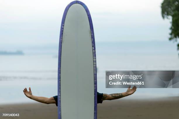 man on the beach behind surfboard - odd one out obscure stock-fotos und bilder