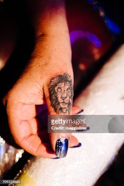 cropped image of woman hand with lion tattoo - lion tattoo stock-fotos und bilder
