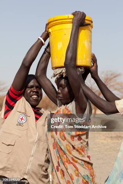 An ICRC worker assists a woman collecting water at Wara village in Pariang County, Unity State, South Sudan where the International Committee of the...