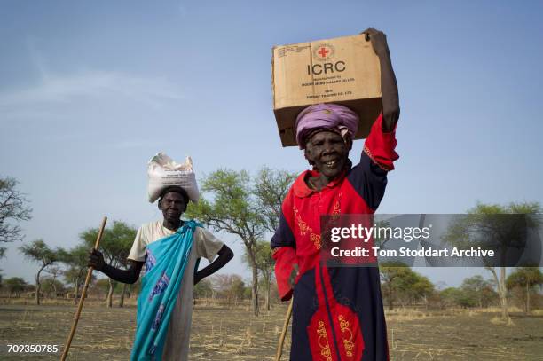 Woman carries a box home during an International Committee of the Red Cross distribution of seeds, agricultural tools and food staples to households...
