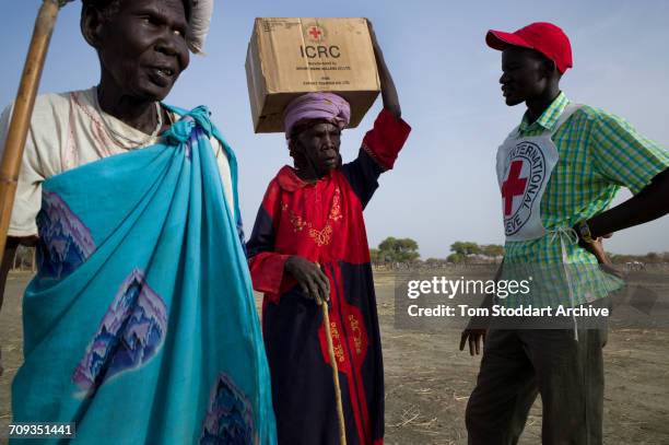 Woman carries a box home during an International Committee of the Red Cross distribution of seeds, agricultural tools and food staples to households...