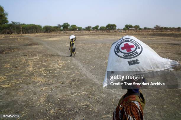 Woman carries a bag home during an International Committee of the Red Cross distribution of seeds, agricultural tools and food staples to households...