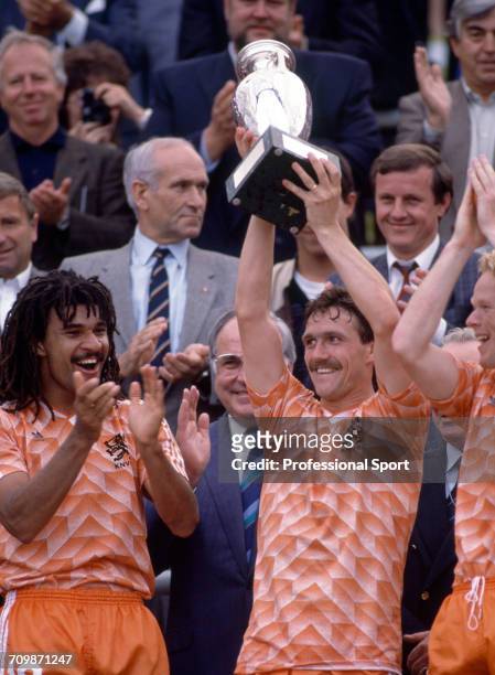 Netherlands football team captain Ruud Gullit applauds as Jan Wouters raises the UEFA European Championship trophy in the air after Netherlands beat...