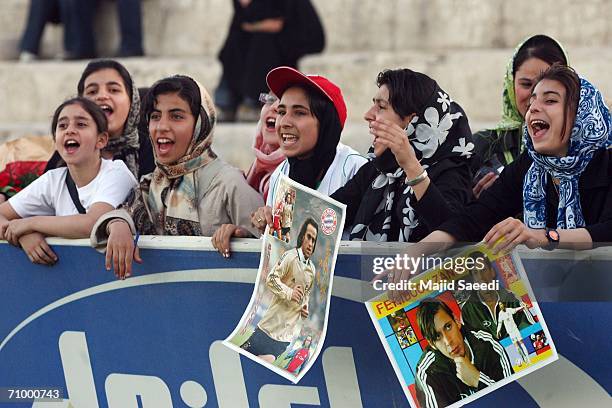 Iranian women hold portraits of Iran's national football players, Ali Karimi and Ferydoon Zandi while watching Iran's national football team exercise...