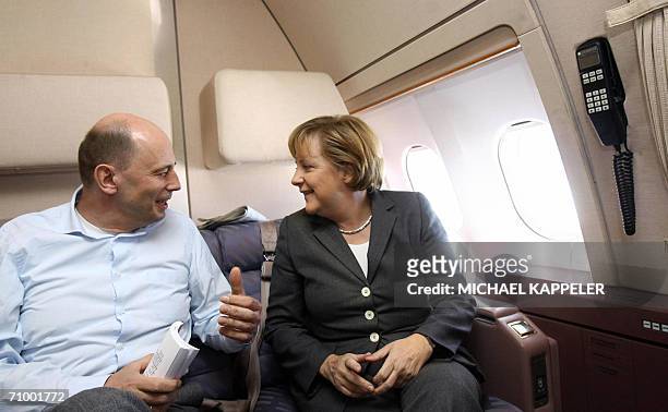 German Chancellor Angela Merkel speaks with German Transport Minister Wolfgang Tiefensee as they fly to Beijing aboard the German aircraft Theodor...