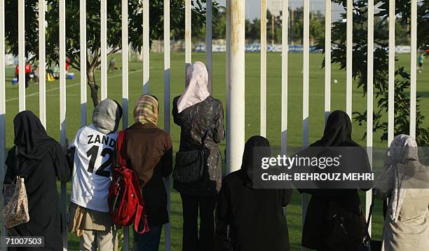 Iranian women watch a training session of Iran's national football team from behind a fence as females were not allowed to enter the stadium at...