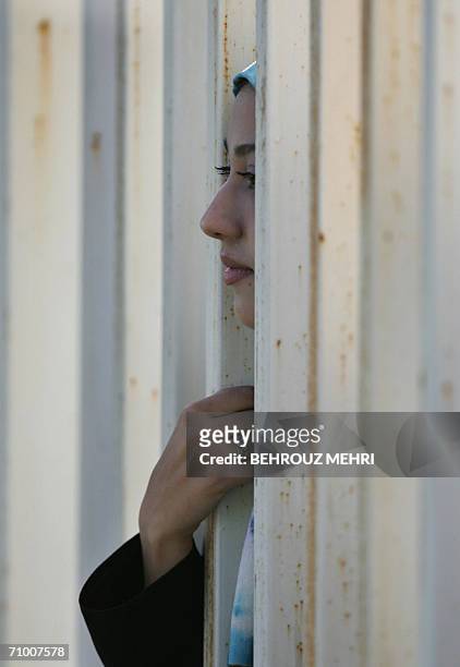 An Iranian woman watches a training session of Iran's national football team from behind a fence as females were not allowed to enter the stadium at...