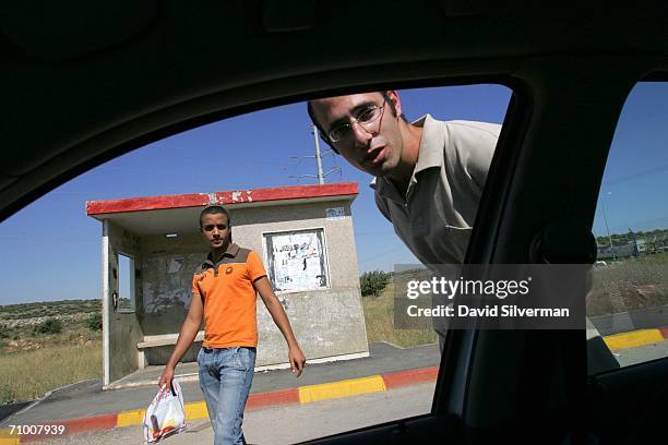 Jewish settlers ask for a ride as they hitch-hike at a bus stop May 22, 2006 at Tapuah Junction in the Samaria region of the West Bank. Israeli...