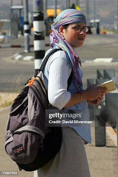 Religious Jewish woman settler reads from her prayer book as she hitch-hikes May 22, 2006 at Tapuah Junction in the Samaria region of the West Bank....