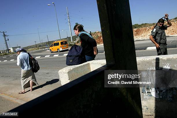 Religious Jewish women settlers hitch-hike at a bus stop where an Israeli border policeman stands guard against Palestinian attacks May 22, 2006 at...