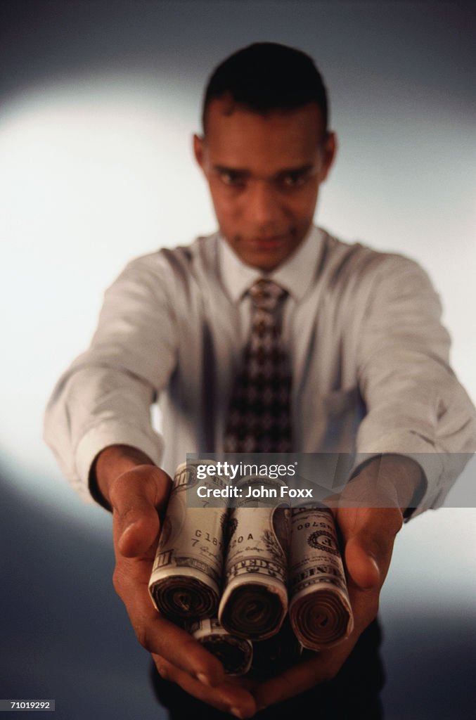 Businessman holding rolled up US banknote