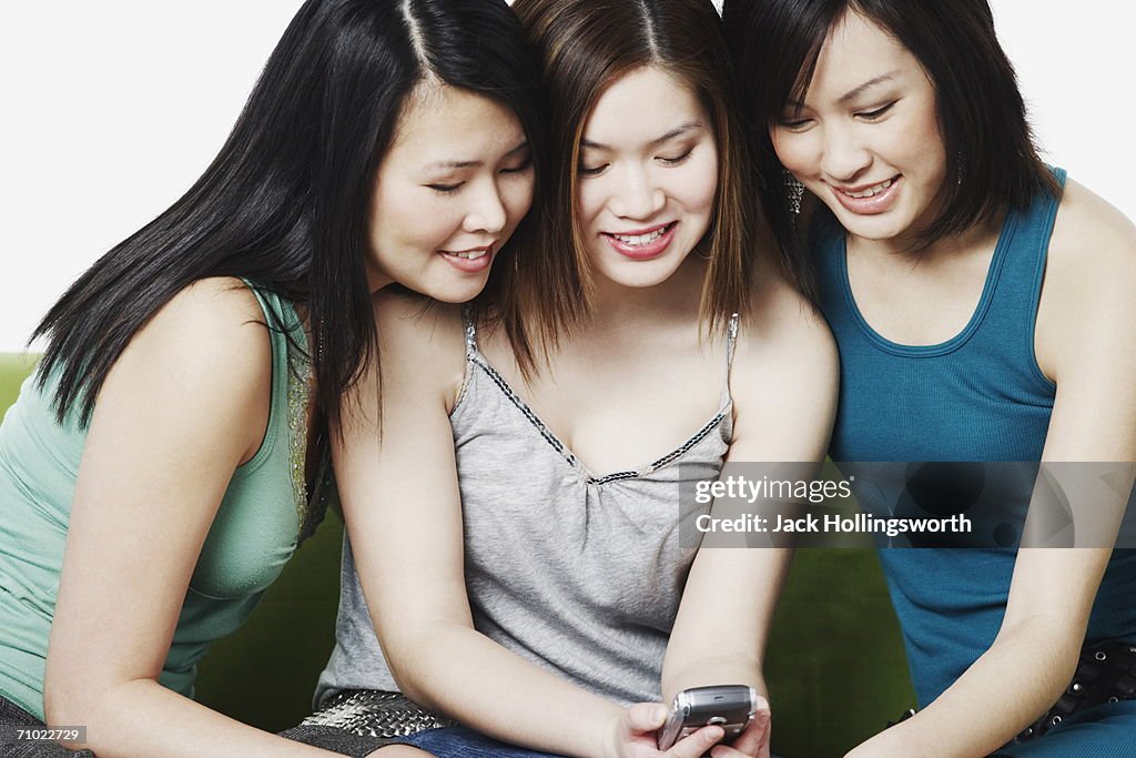 Close-up of three young women holding a mobile phone