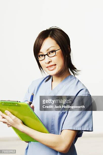 portrait of a female doctor holding a clip board and a pen - clipboard and glasses stock pictures, royalty-free photos & images