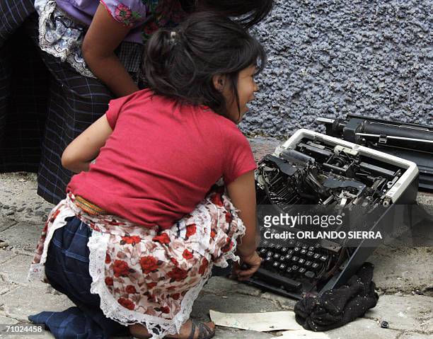 Dos ninas indigenas juegan con una maquina de escribir rota propiedad de la Policia Nacional Civil y que quedo tirada en la avenida principal del...