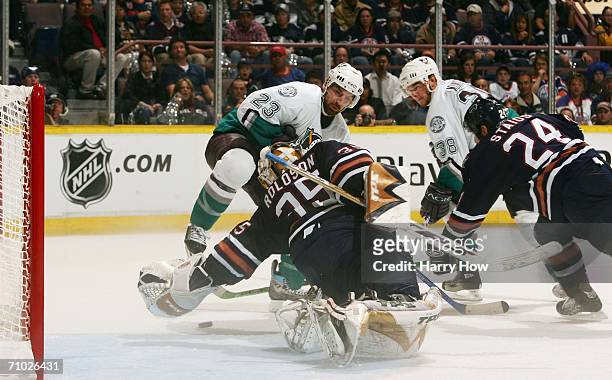 Chris Kunitz of the Mighty Ducks of Anaheim slides the puck under Dwayne Roloson of the Edmonton Oilers as Rusian Salei and Steve Staios watch in the...