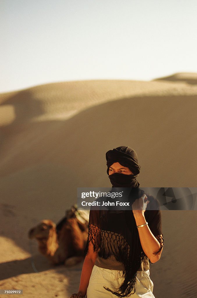 Young woman in desert with camel in background