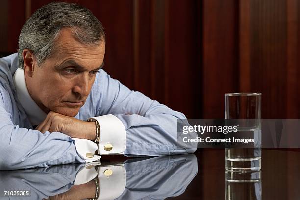 businessman looking pessimistically at a glass of water - pessimism stock pictures, royalty-free photos & images