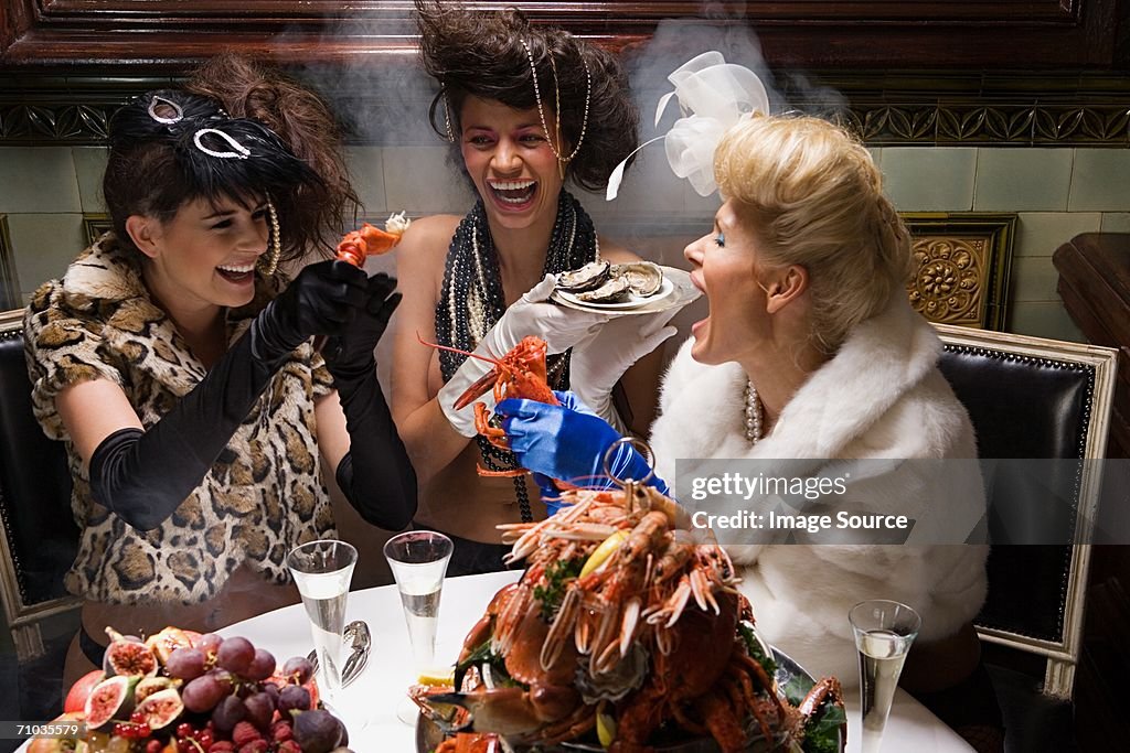 Three women tearing apart lobster