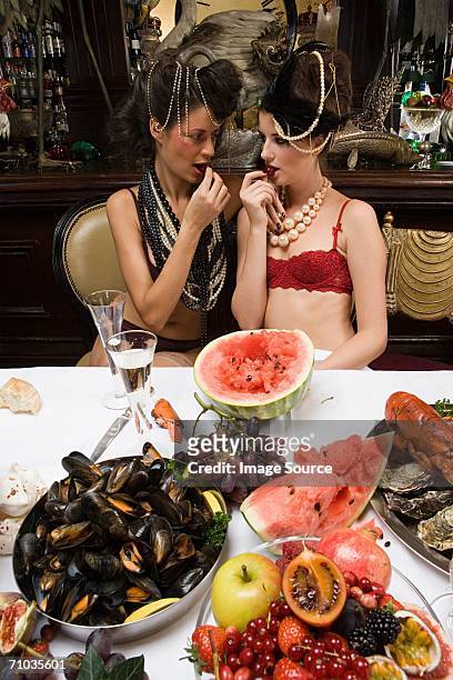 dos mujeres usar ropa interior disfrutar de un banquete - mujer seductora fotografías e imágenes de stock