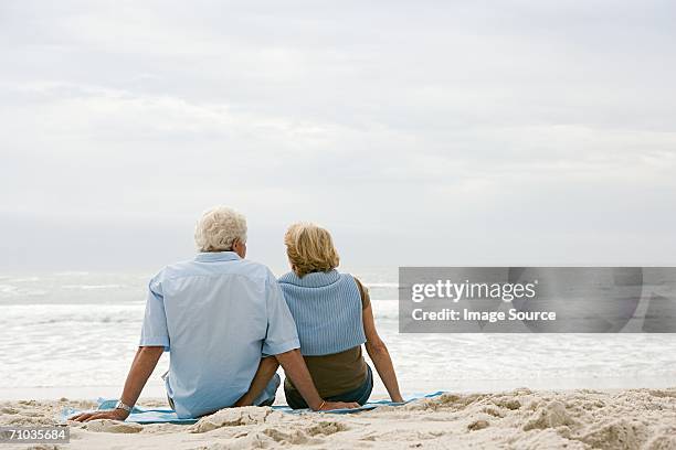 senior couple sitting on a beach - woman day dreaming stockfoto's en -beelden