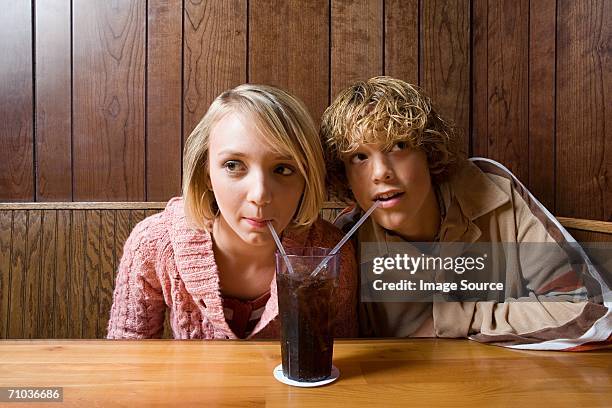 teenage couple sharing a soft drink - soft drink stock-fotos und bilder
