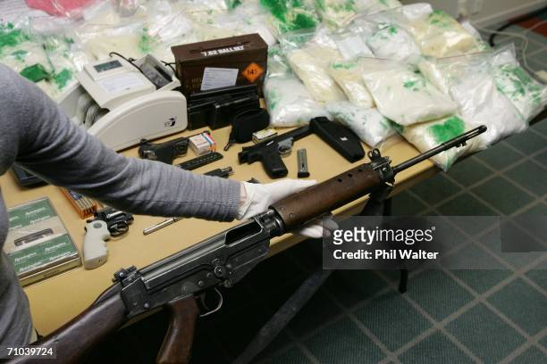 An exhibits expert holds an M16 semiautomatic rifle before a table holding 95 kilos of crystal methamphetamine, 150 kilos of pseudoephedrine and a...