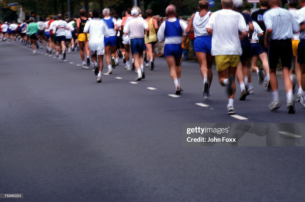 Marathon runners on road, rear view