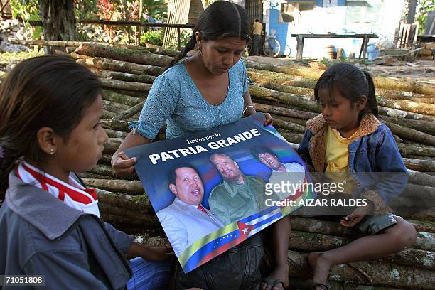 Una indigena quechua observa junto a sus hijos un afiche con fotos de los presidentes Hugo Chavez de Venezuela, Fidel Castro de Cuba y Evo Morales de...