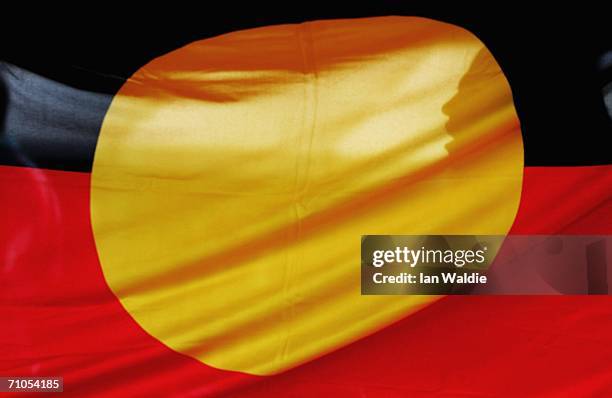 Woman is silhouetted behind the Aboriginal flag during an event to mark Sorry Day May 26, 2006 in Sydney, Australia. The first National Sorry Day was...