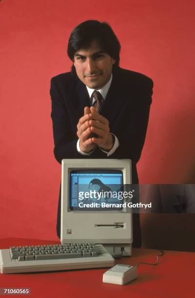 American computer magnate and co-founder of Apple Computer Steve Jobs leans on the his Macintosh 128K, the original Macintosh personal computer,...