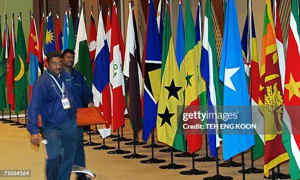 Workers walk past Non-Aligned Movement member country flags at the International Convention Center in Putrajaya, 27 May 2006. Malaysia said that...