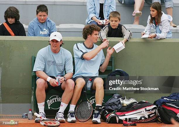 Andy Murray of Great Britain signs an autograph for a fan as he sits with his coach Leon Smith during practice prior to the French Open at Roland...
