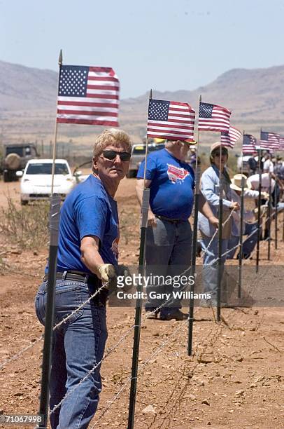 Volunteers of the Minuteman Civil Defense Corp. Put up barb-wire on new fencing topped by American flags on May 27, 2006 in Palominas, Arizona. This...