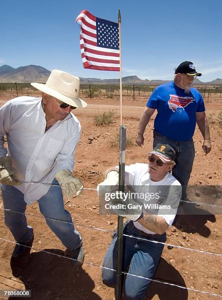 Frank Castro of Arizona and Sam Wright, both volunteers of the Minuteman Civil Defense Corp. Put up barb wire on new fencing topped by American flags...