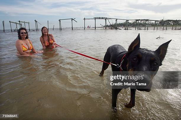 Marty Mansfield , Laura Miller and Lola the dog cool off in the water in front of a pier destroyed by Hurricane Katrina May 27, 2006 in Waveland,...