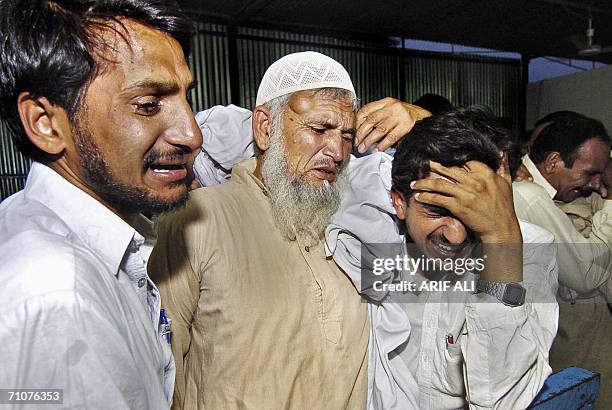 Relatives weep beside the coffins of two Pakistani workers Muneer Ahmed and Nasar Iqbal Mattu, after their bodies arrived 30 May 2006 in Lahore...