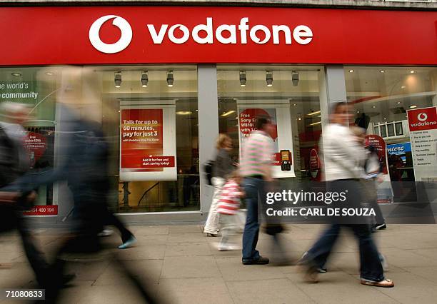 Shoppers walk past a Vodafone store in London 30 May 2006. Vodafone, the world's biggest mobile phone company, reported today the biggest annual net...