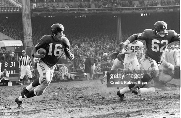 New York Giants football player Frank Gifford runs with protection from teammate Darrell Dess during a game against the Philadelphia Eagles, 1960s.