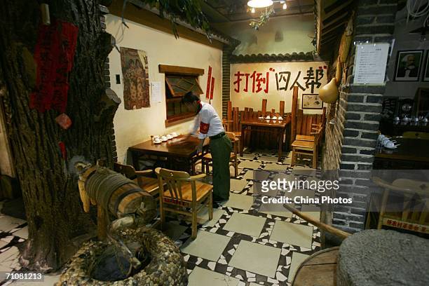 An attendant cleans in front of a slogan reading: "Beat down the Gang of Four " at a Chinese Cultural Revolution-themed restaurant May 30, 2006 in...